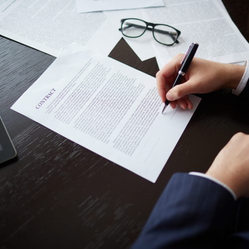 Signing contract Image of businessman hand with pen signing contract at workplace